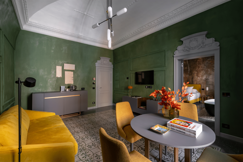 Stylish Bari hotel room with green walls, yellow sofa, and modern decor. Best hotels Bari Italy.