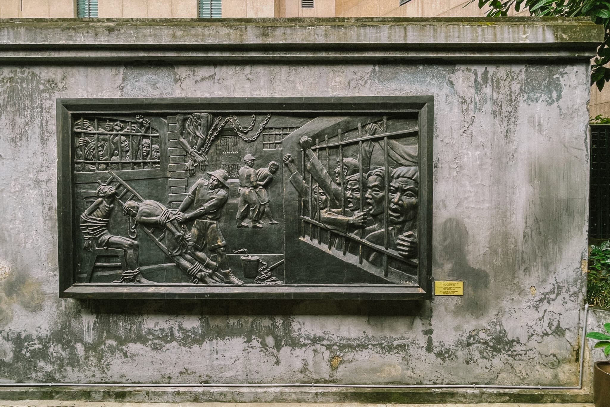 Hoa Lo Prison memorial in Hanoi, Vietnam. A dark relief sculpture showing prison conditions. Hanoi hidden gems.