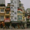 Hanoi street scene with colorful buildings and motorbikes. OSEVEN sign visible.