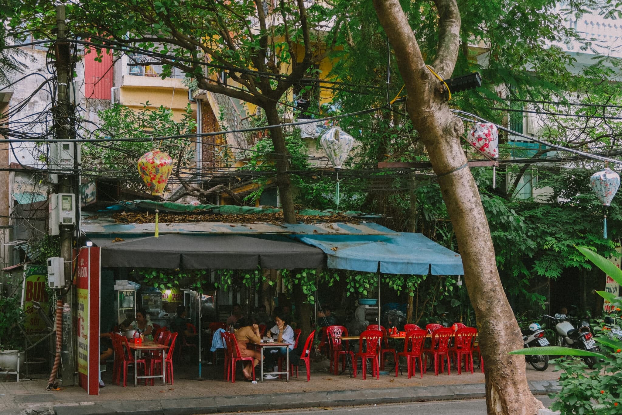 Hanoi street food cafe with red chairs and lanterns, a hidden gem.