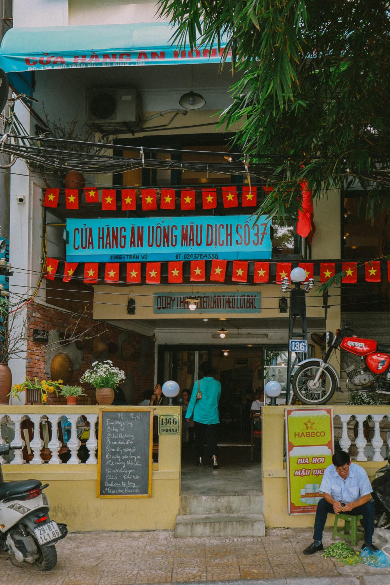 Hanoi hidden gem: Local restaurant "Cua Hang An Uong Mau Dich So 37" with Vietnamese flags. Things to do in Hanoi.