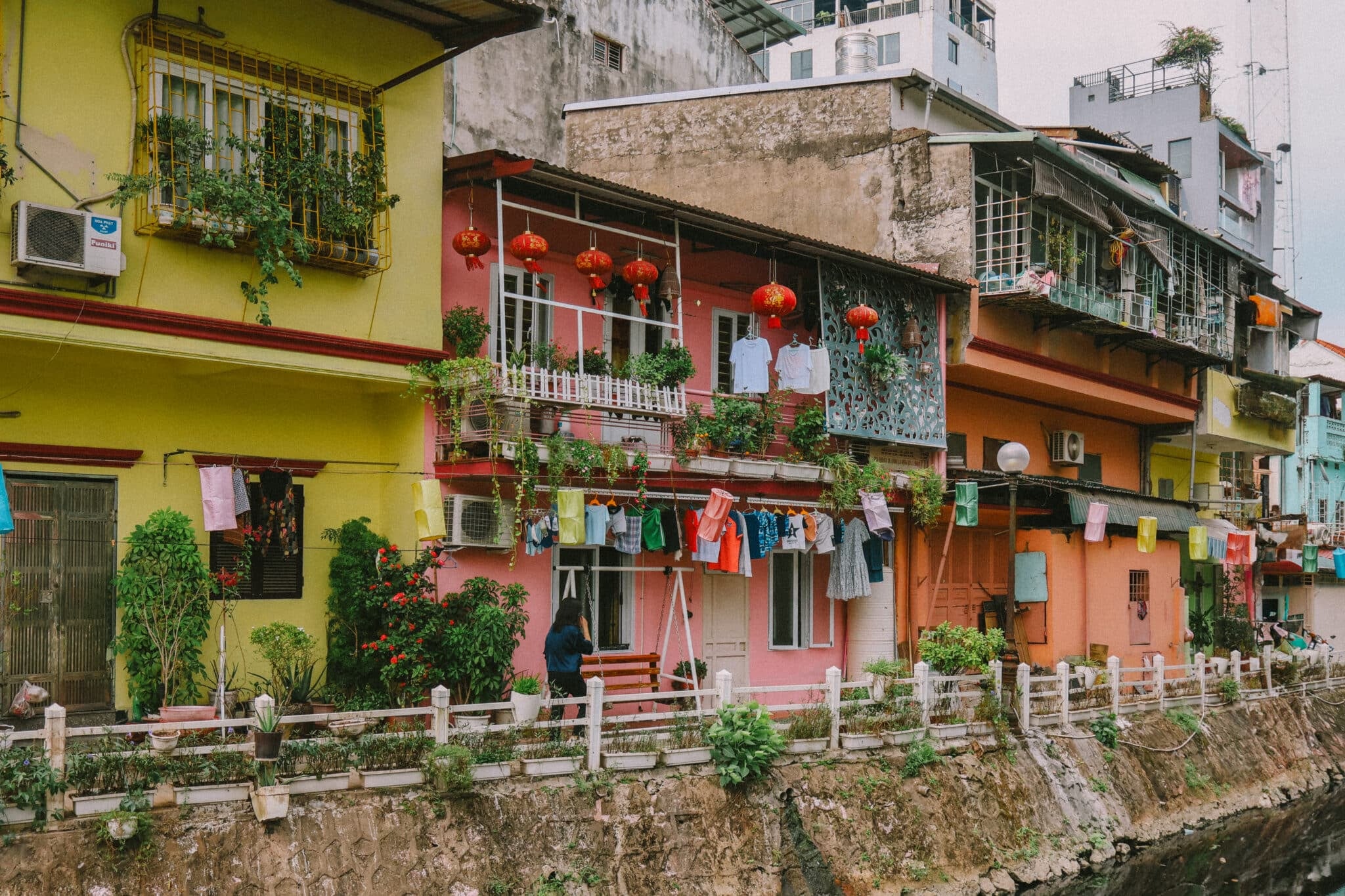 Colorful Hanoi houses line a canal with hanging laundry. Discover hidden gems and unique things to do in Hanoi, Vietnam.