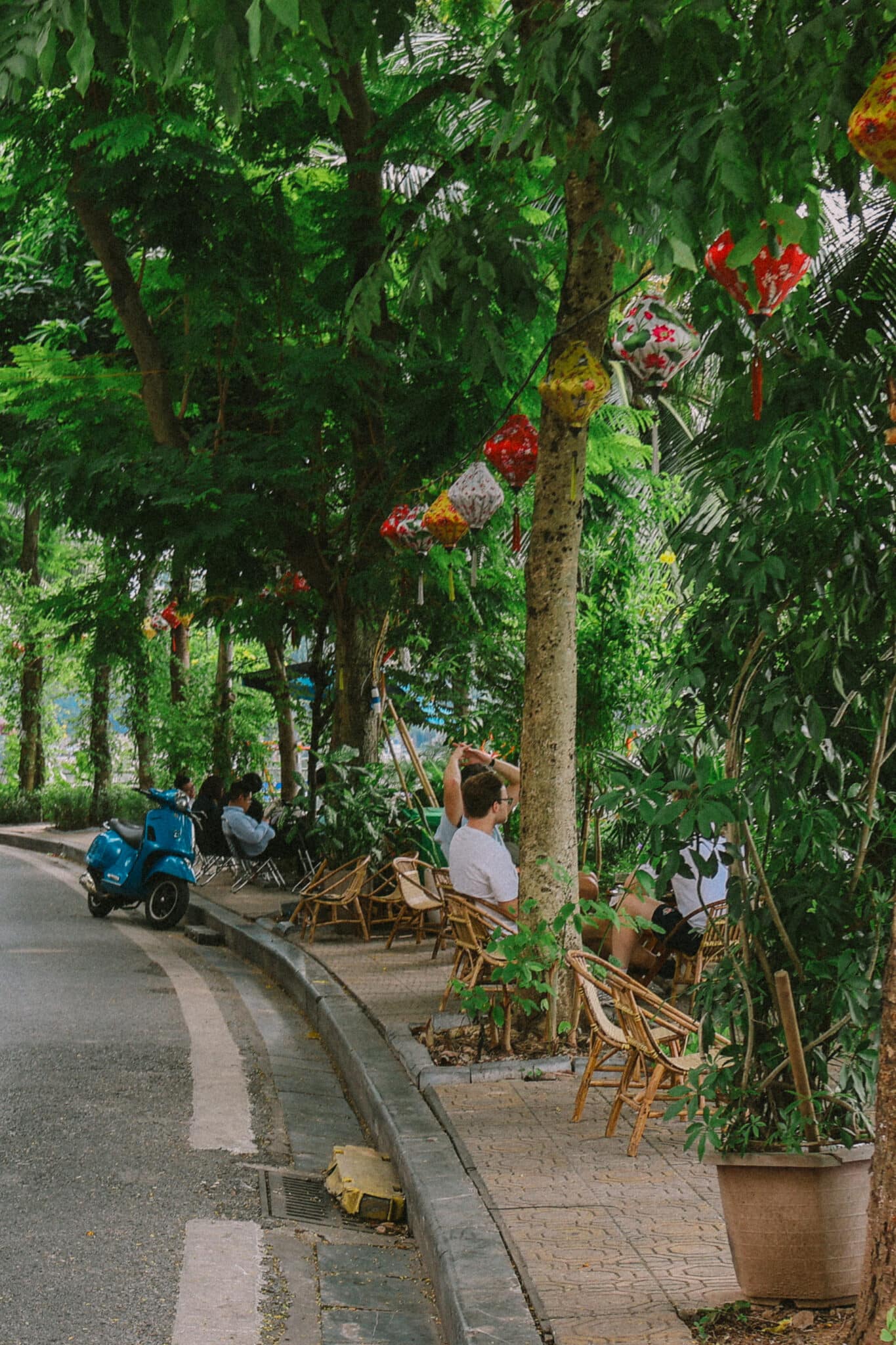 Hanoi street cafe in Truc Bach with lanterns and a blue scooter.