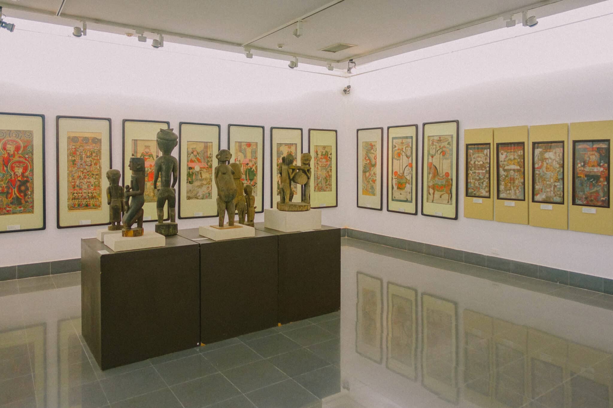 Hanoi museum display with sculptures and framed artwork, showcasing Vietnamese culture.