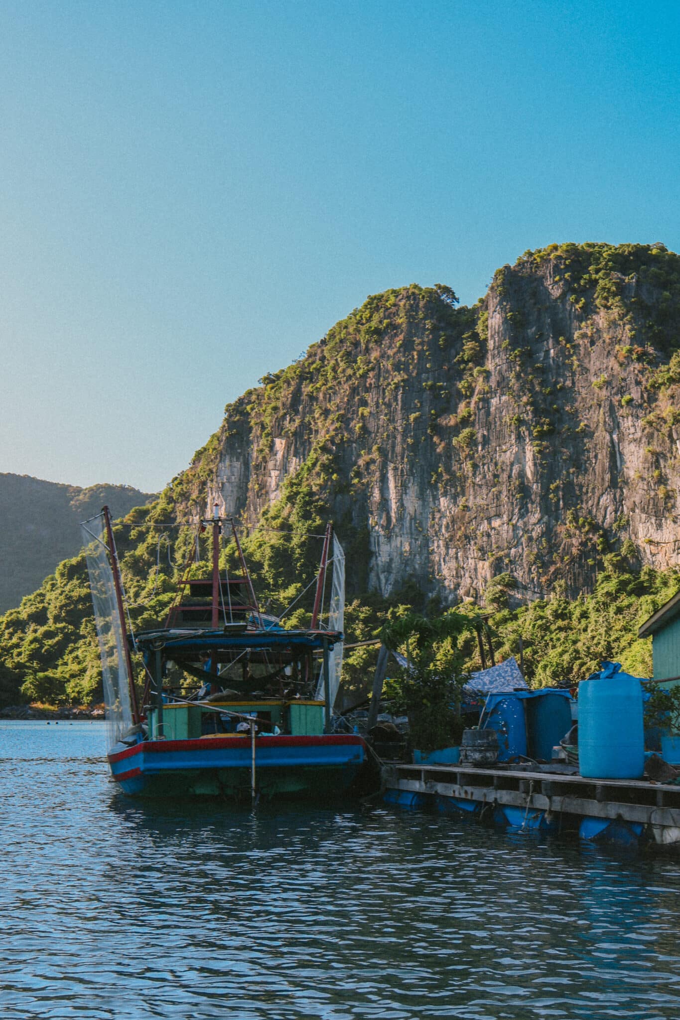 L'Amour Junk boat docked at a floating pier with karst mountains in Ha Long Bay