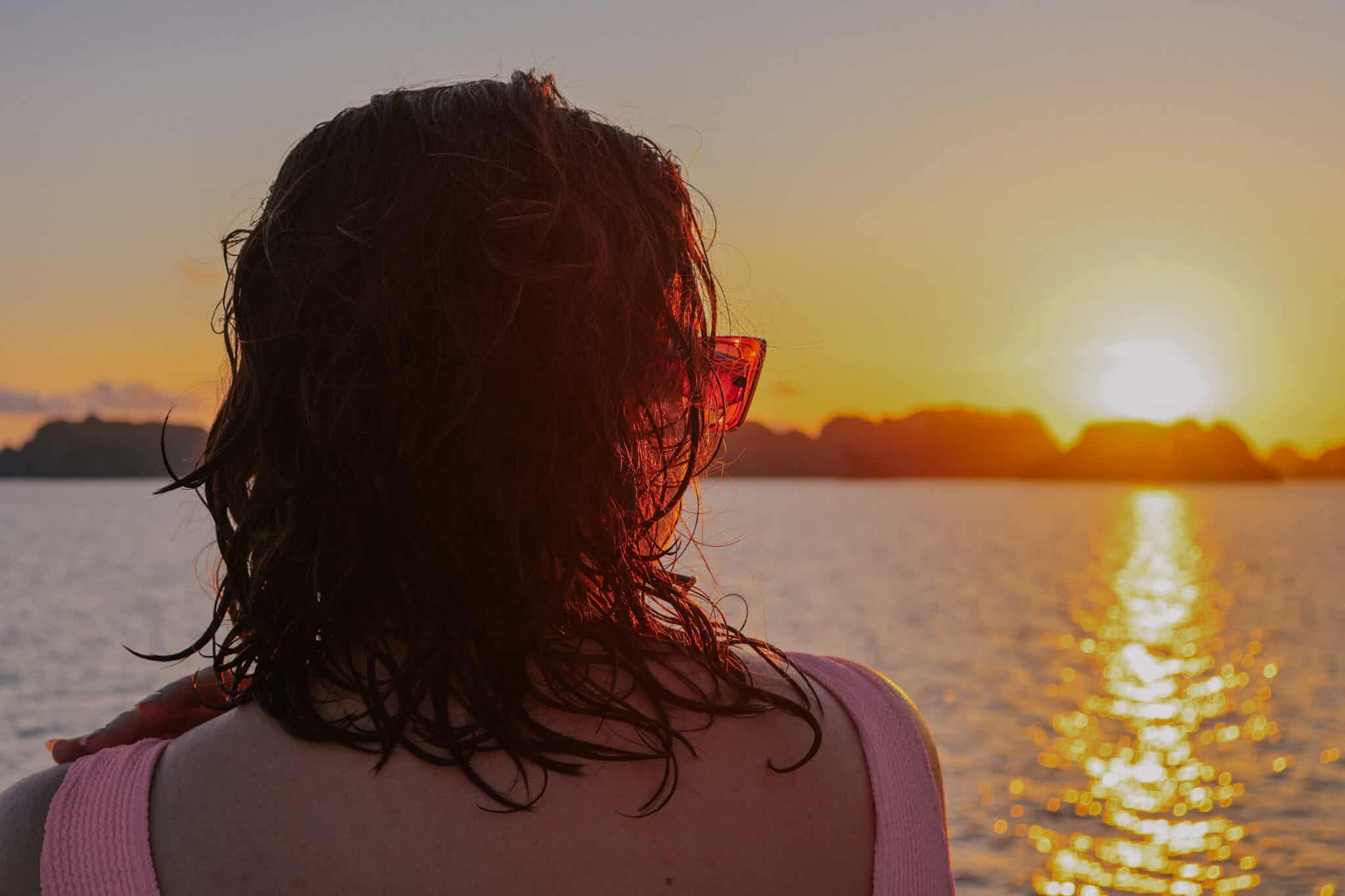Woman watches sunset on a private Ha Long Bay cruise on L'Amour Junk.