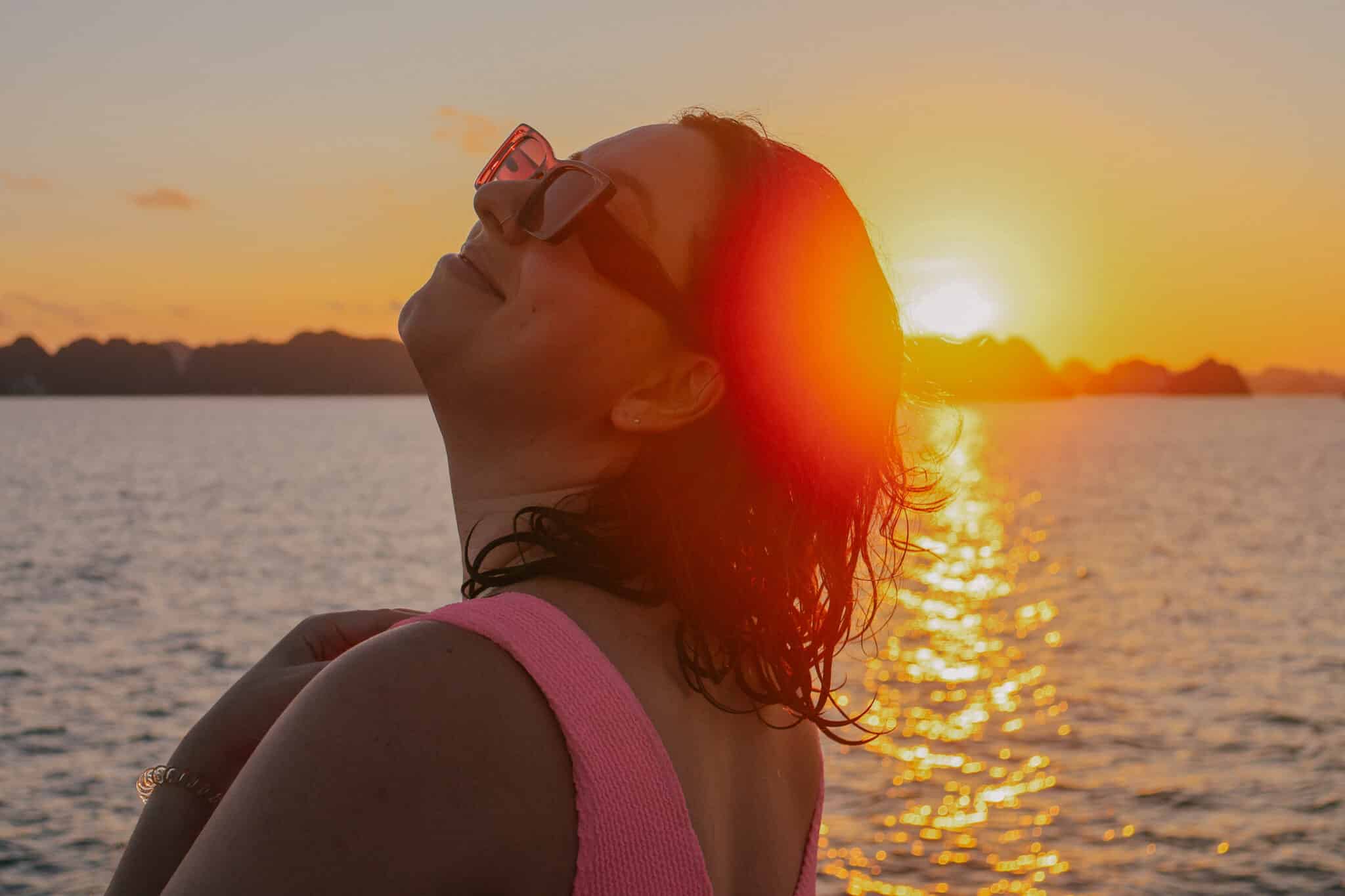 Woman enjoying sunset on a private Ha Long Bay cruise on L'Amour Junk