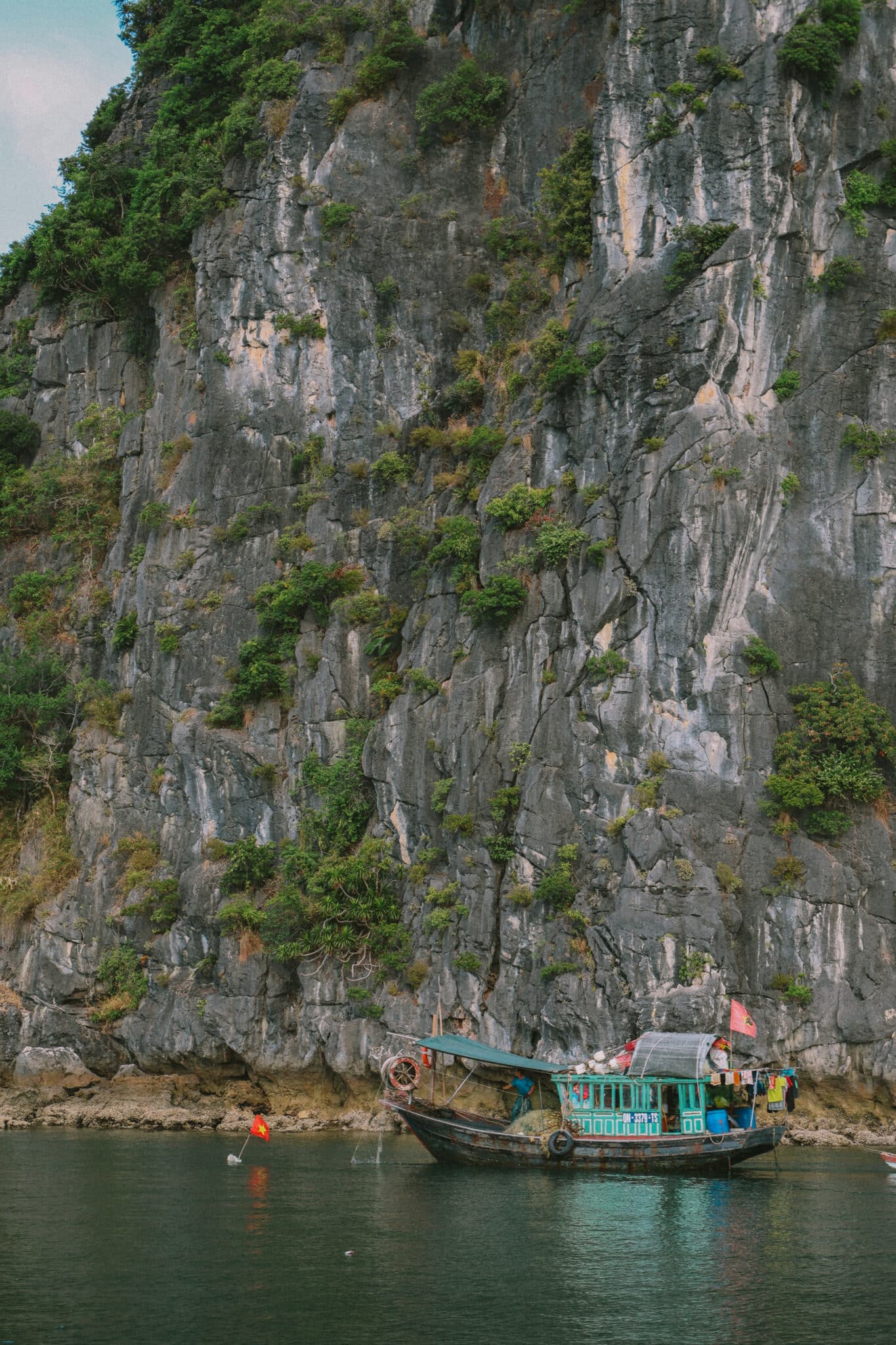 L'Amour Junk boat on a private Ha Long Bay cruise near a limestone cliff