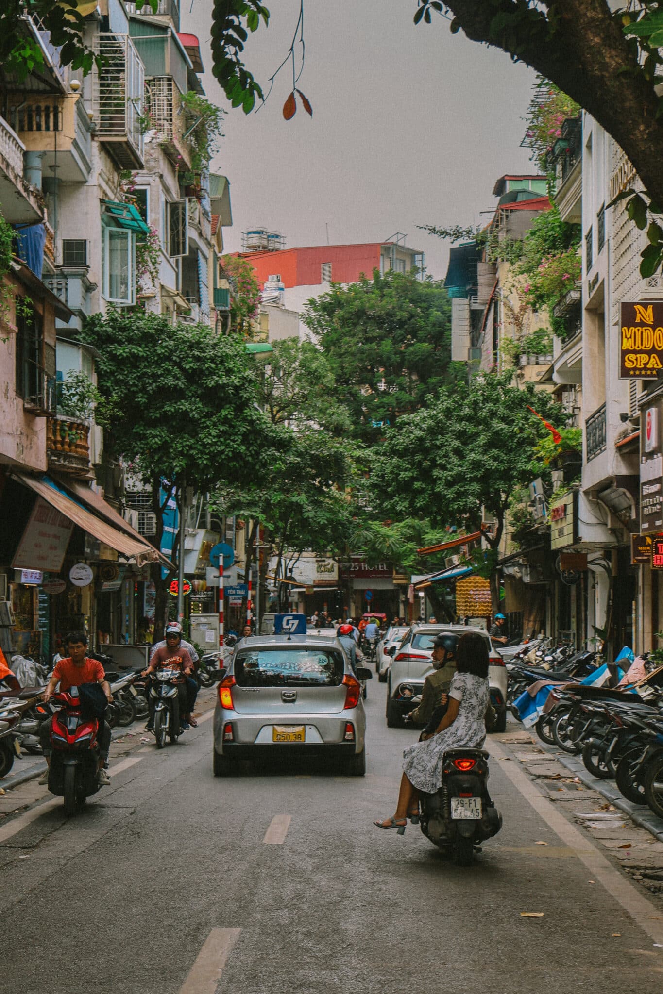 Busy street in Hanoi Old Quarter with motorbikes and cars.