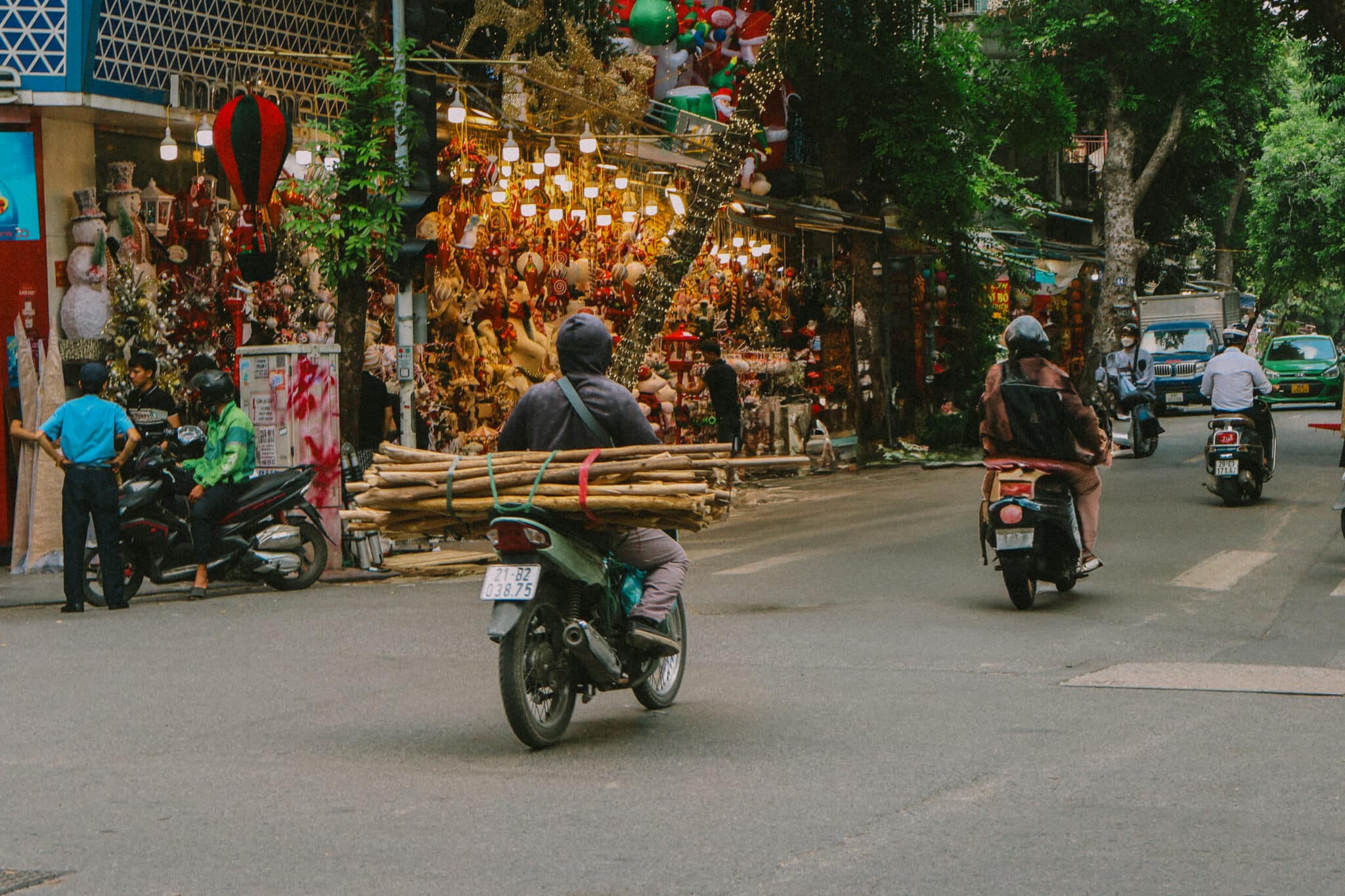 Motorcyclist carrying wood through Hanoi Old Quarter's bustling street