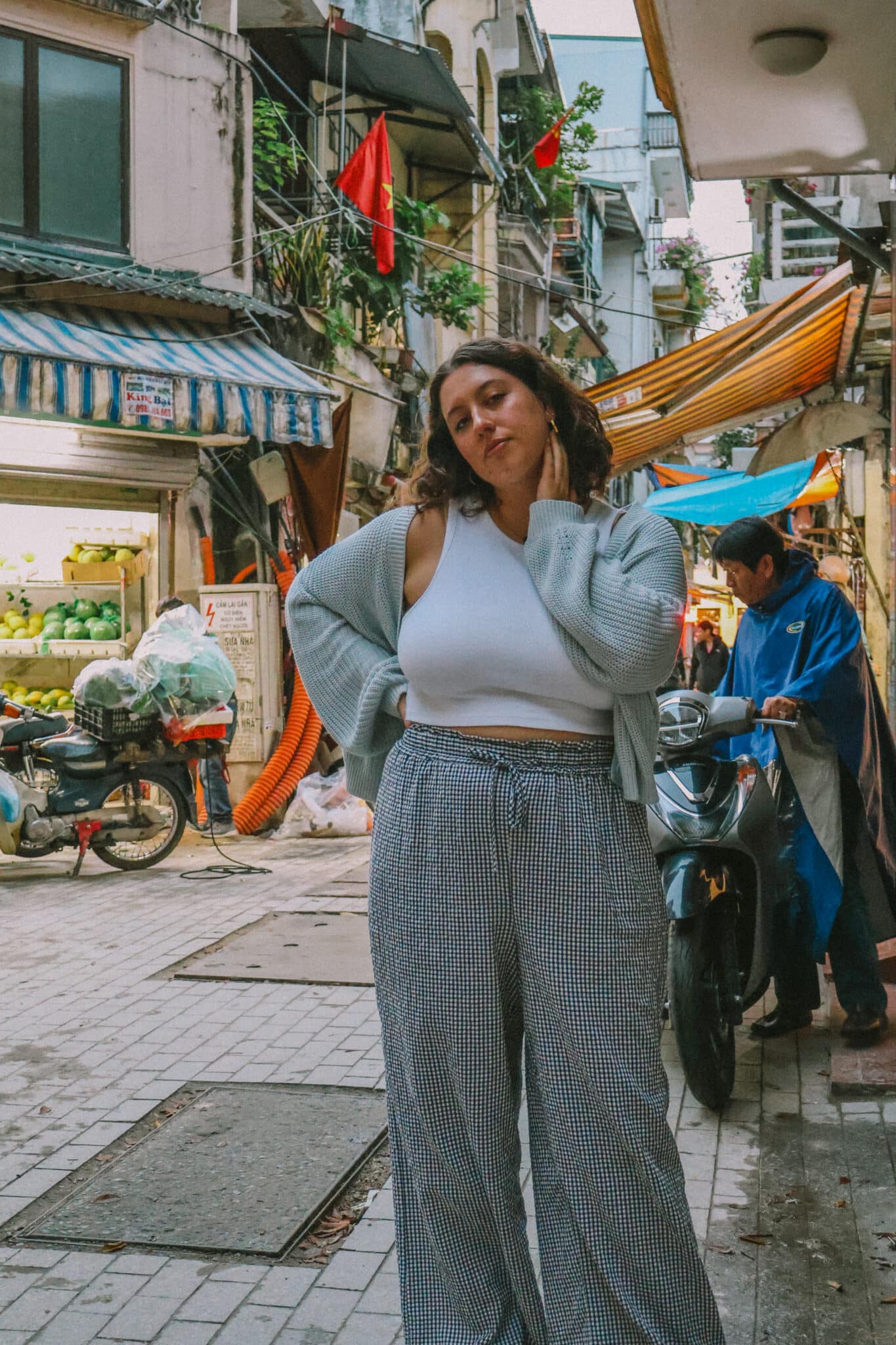 Woman in Hanoi Old Quarter street with shops and motorbikes