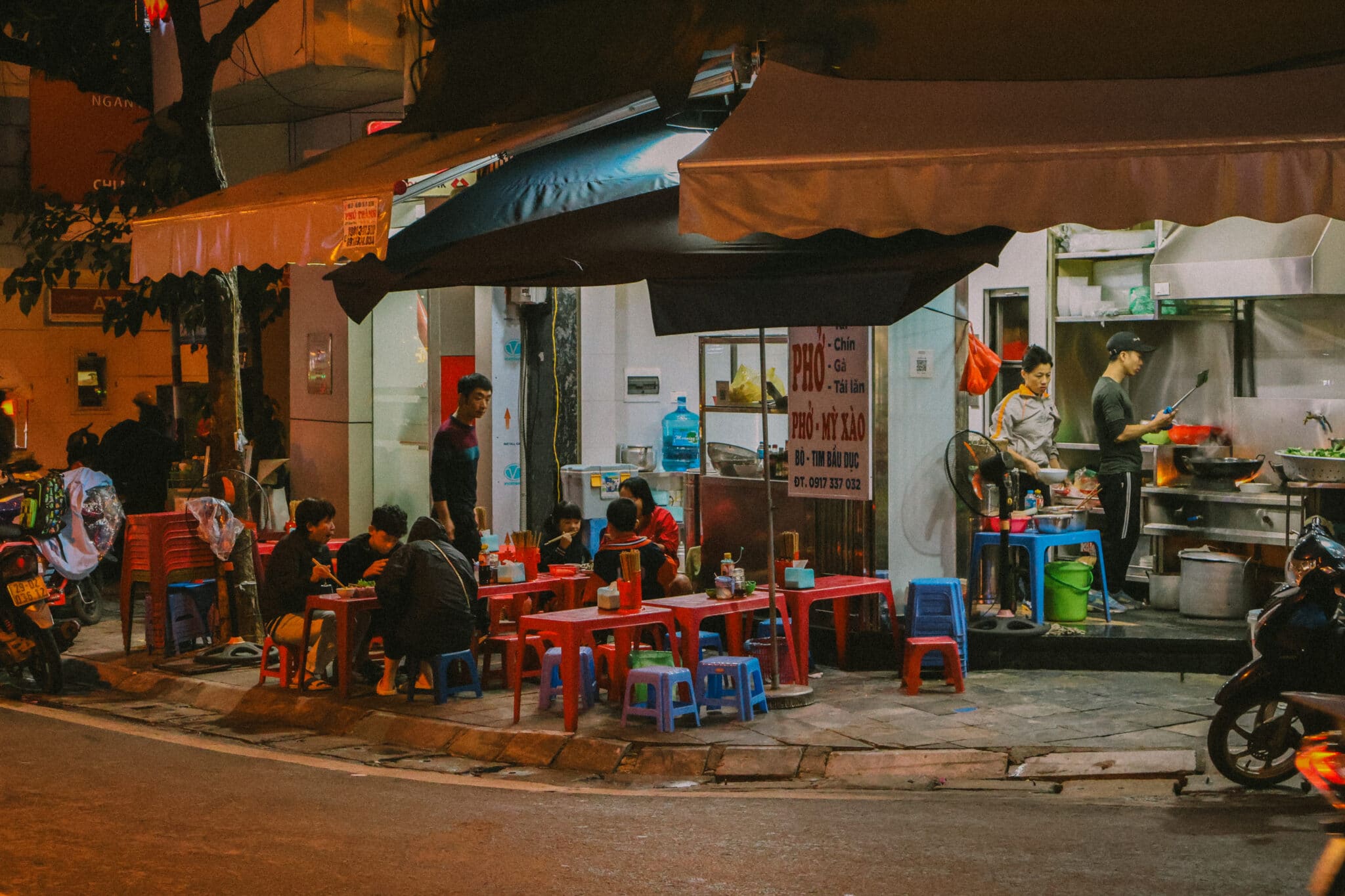 Hanoi Old Quarter street food scene at night with people eating pho
