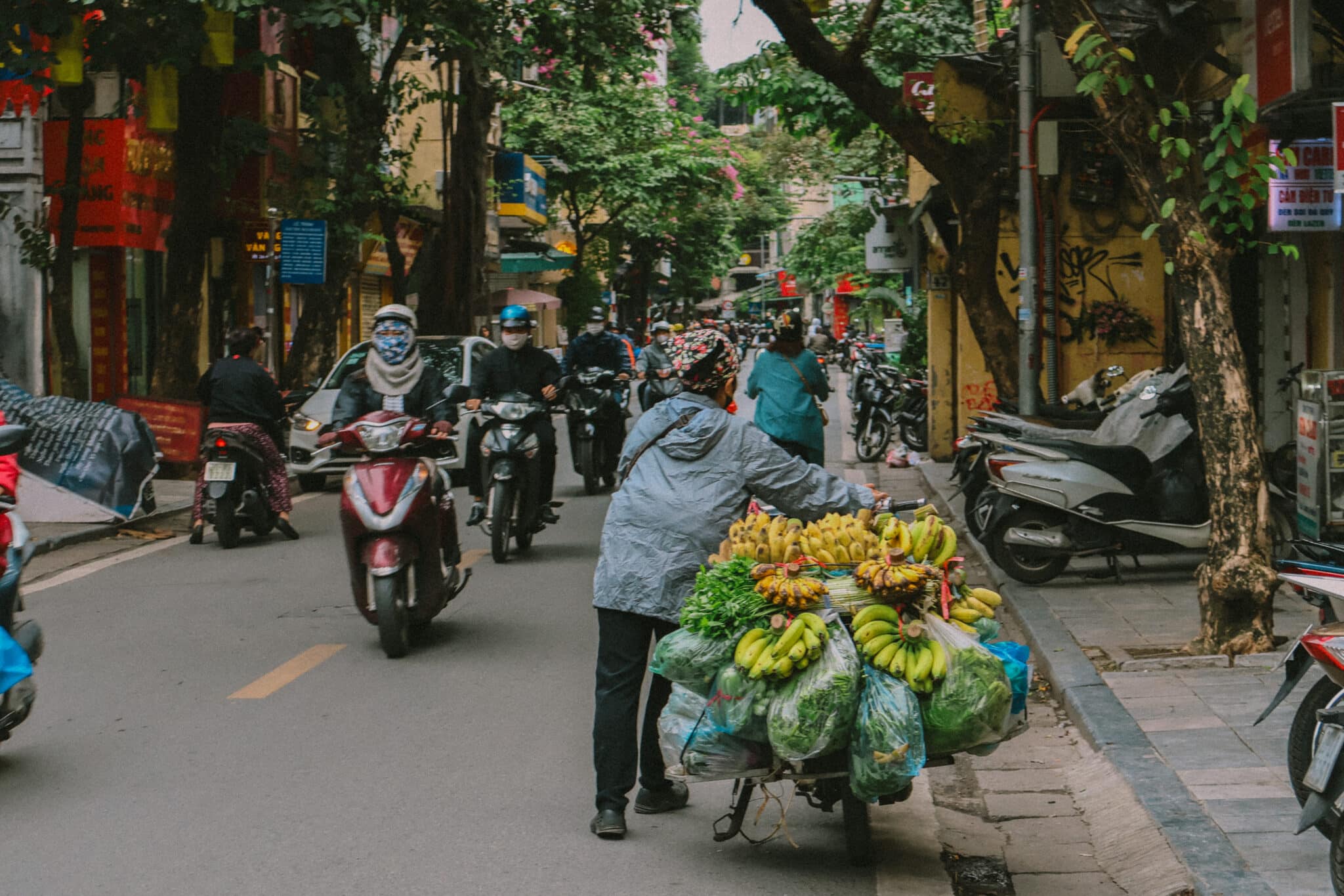 Busy street scene in Hanoi Old Quarter with motorbikes and fruit vendor