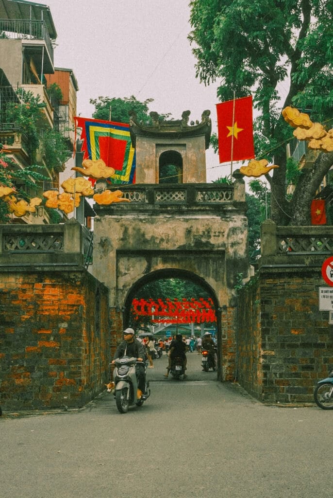 Hanoi Old Quarter gate with motorbikes and flags