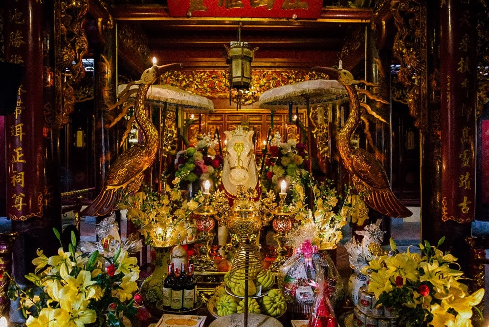 Ornate altar with golden cranes and flowers in Hanoi Old Quarter