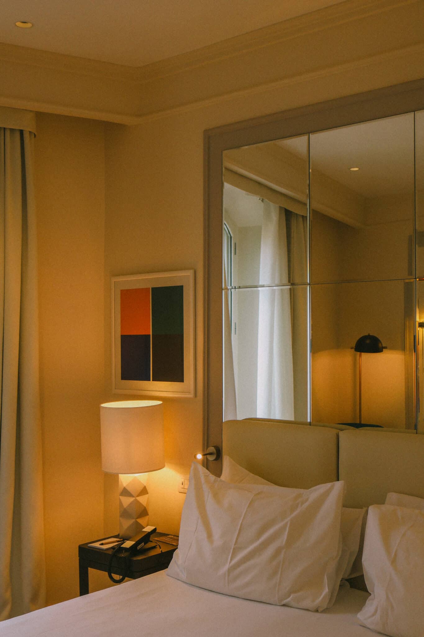 Rome hotel room with bed, lamp, and modern art, perfect for a Jet2CityBreak to Rome.