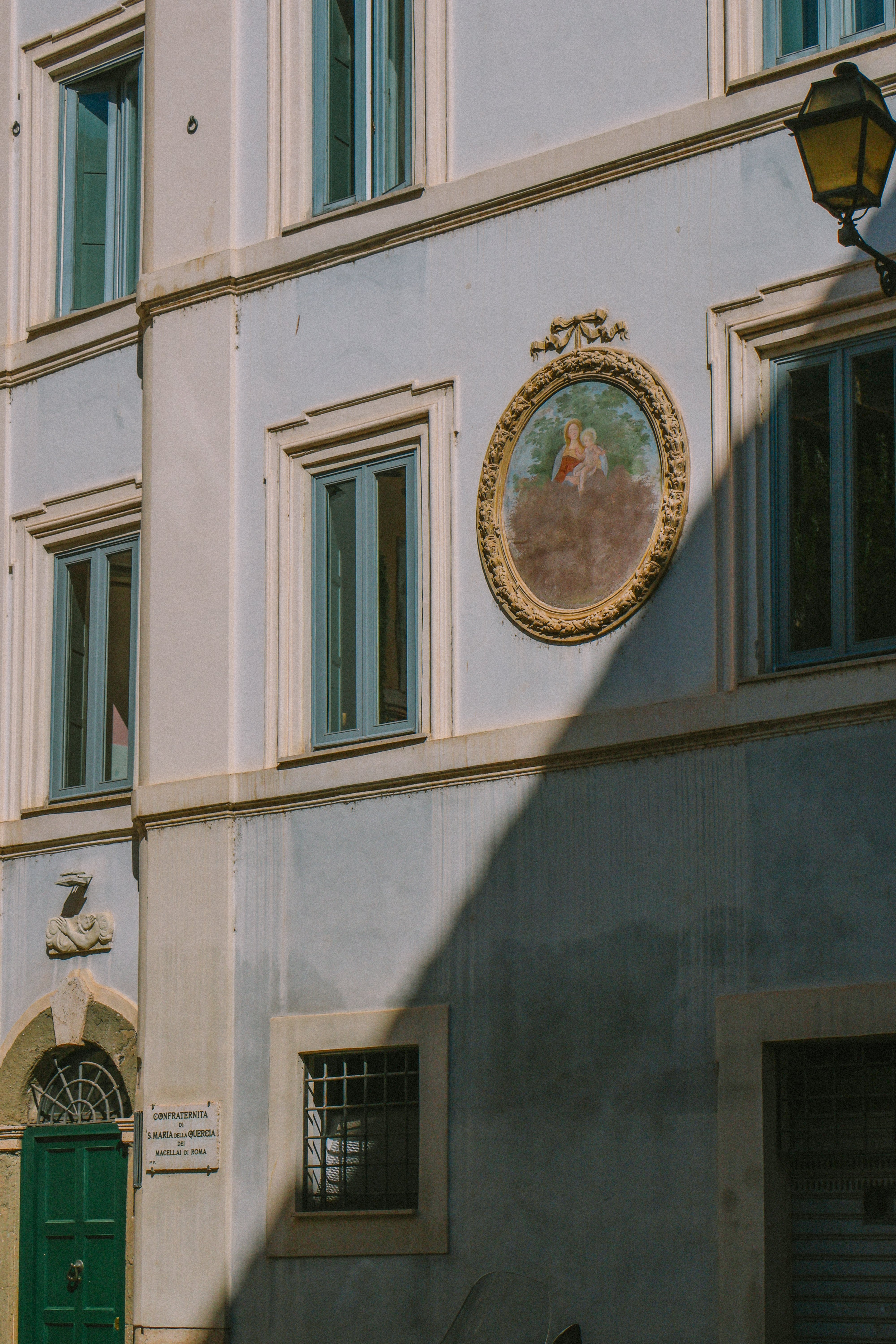 Rome building facade with Madonna painting and blue window frames.