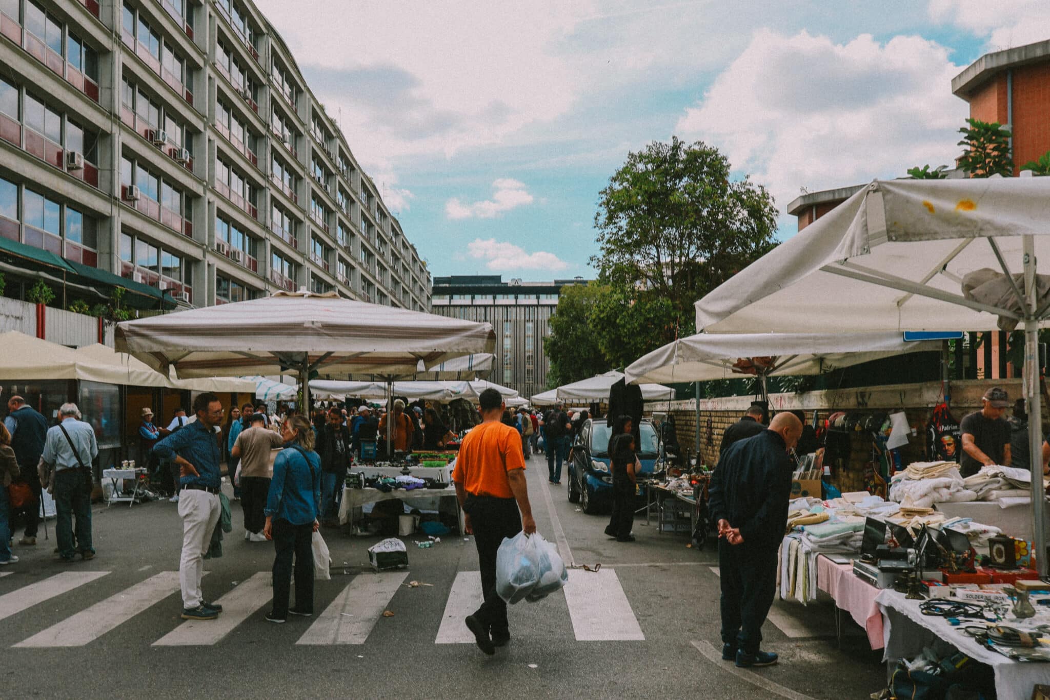 Rome Porta Portese flea market scene with stalls, people, and urban buildings.
