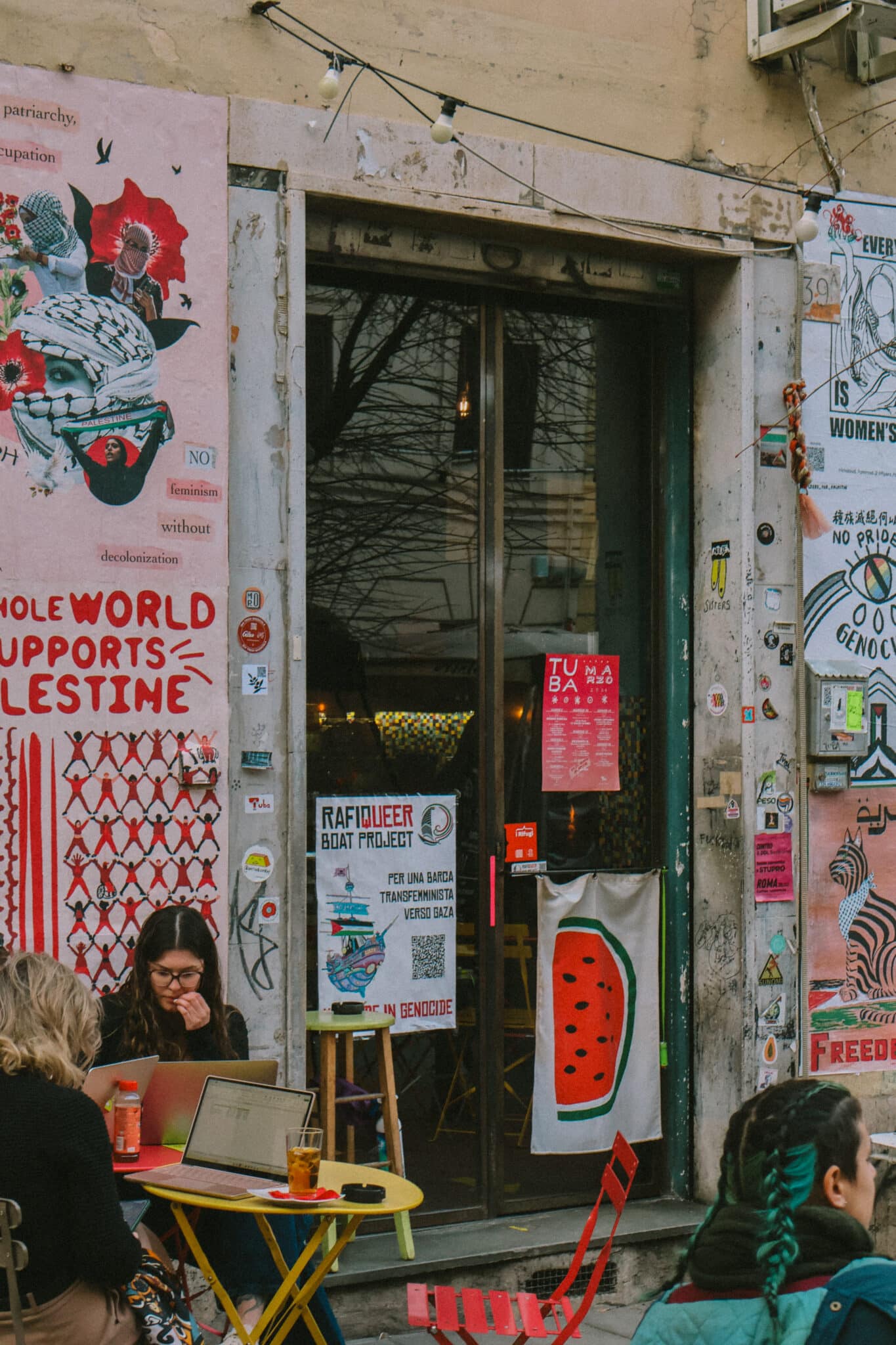 Street art and cafe in Rome. "Whole World Supports Palestine" mural.