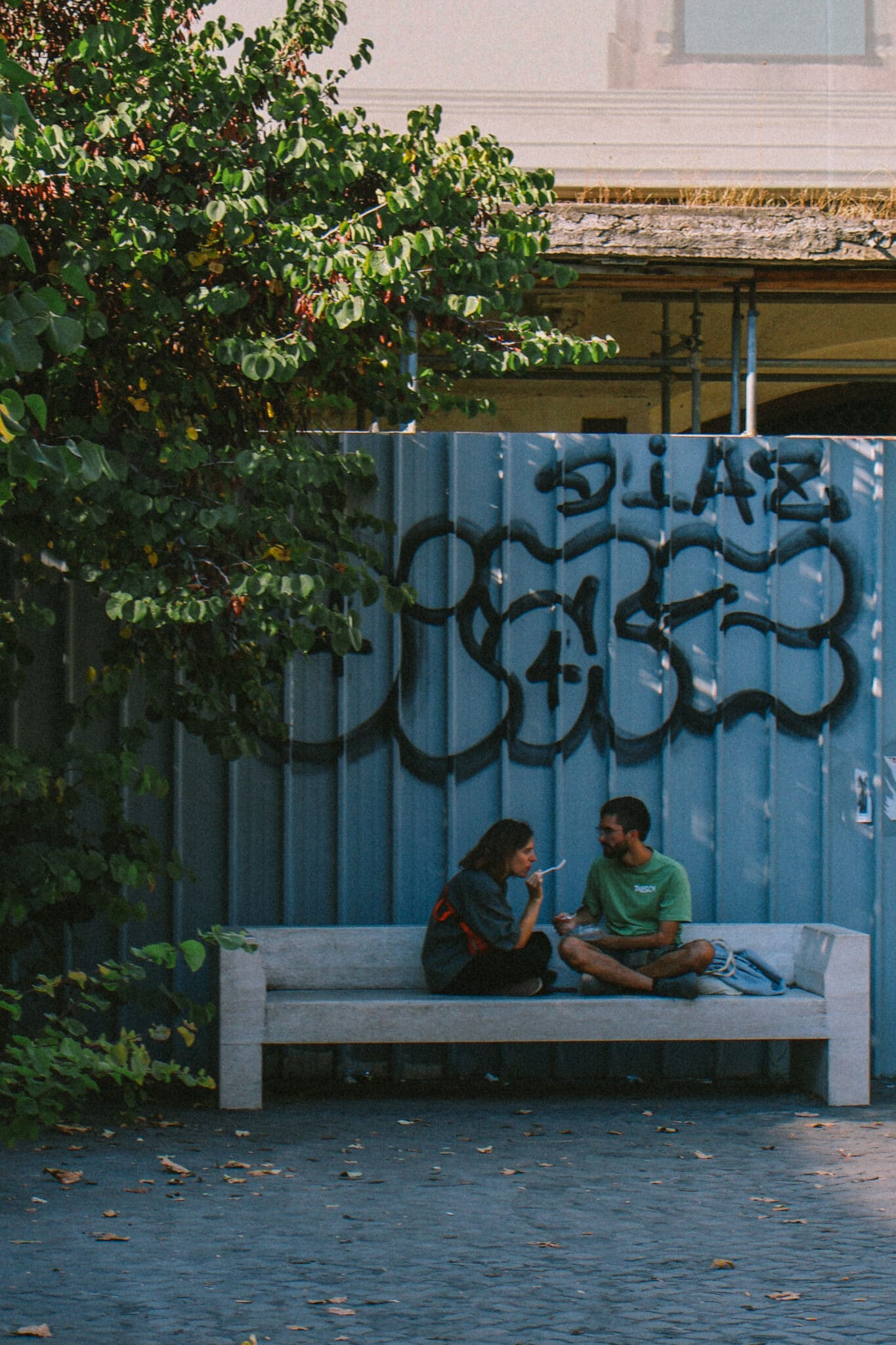 Couple on a bench in Rome near graffiti wall. Jet2CityBreak to Rome.