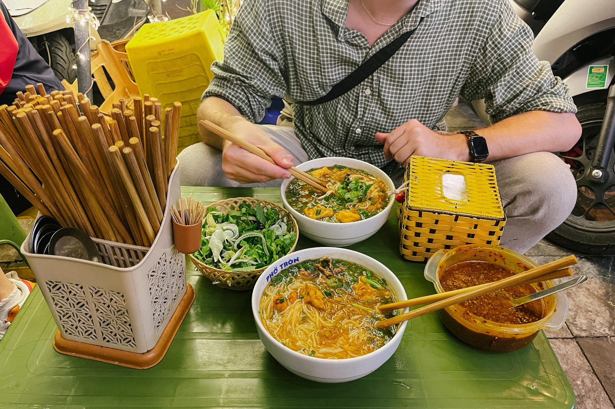 Two bowls of bun rieu at a Hanoi restaurant, Bun Rieu Pho Co, with chopsticks and condiments
