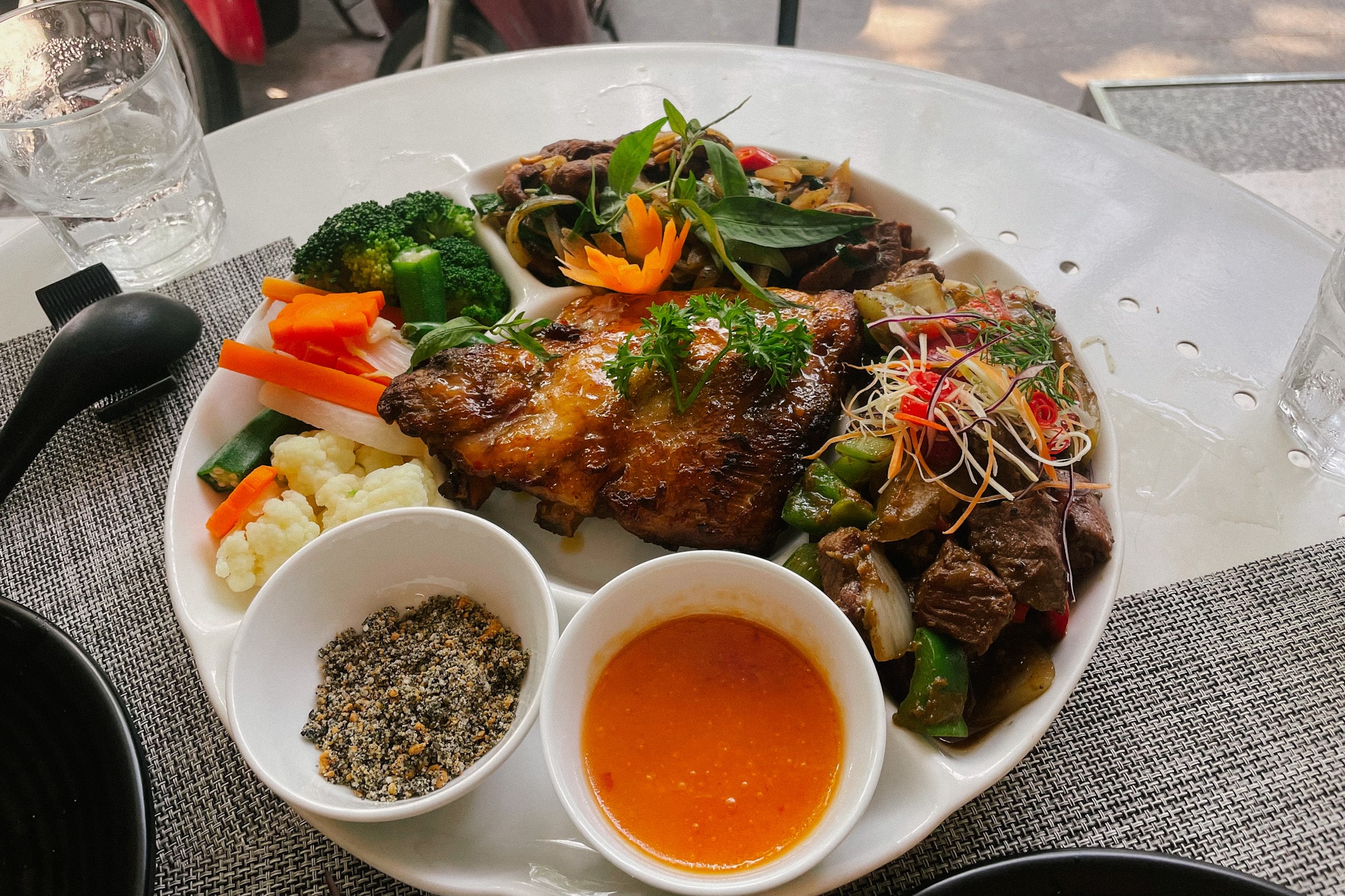 Vietnamese food platter from a Hanoi restaurant, featuring grilled meat, vegetables, and dipping sauce at Koto Van Mieu