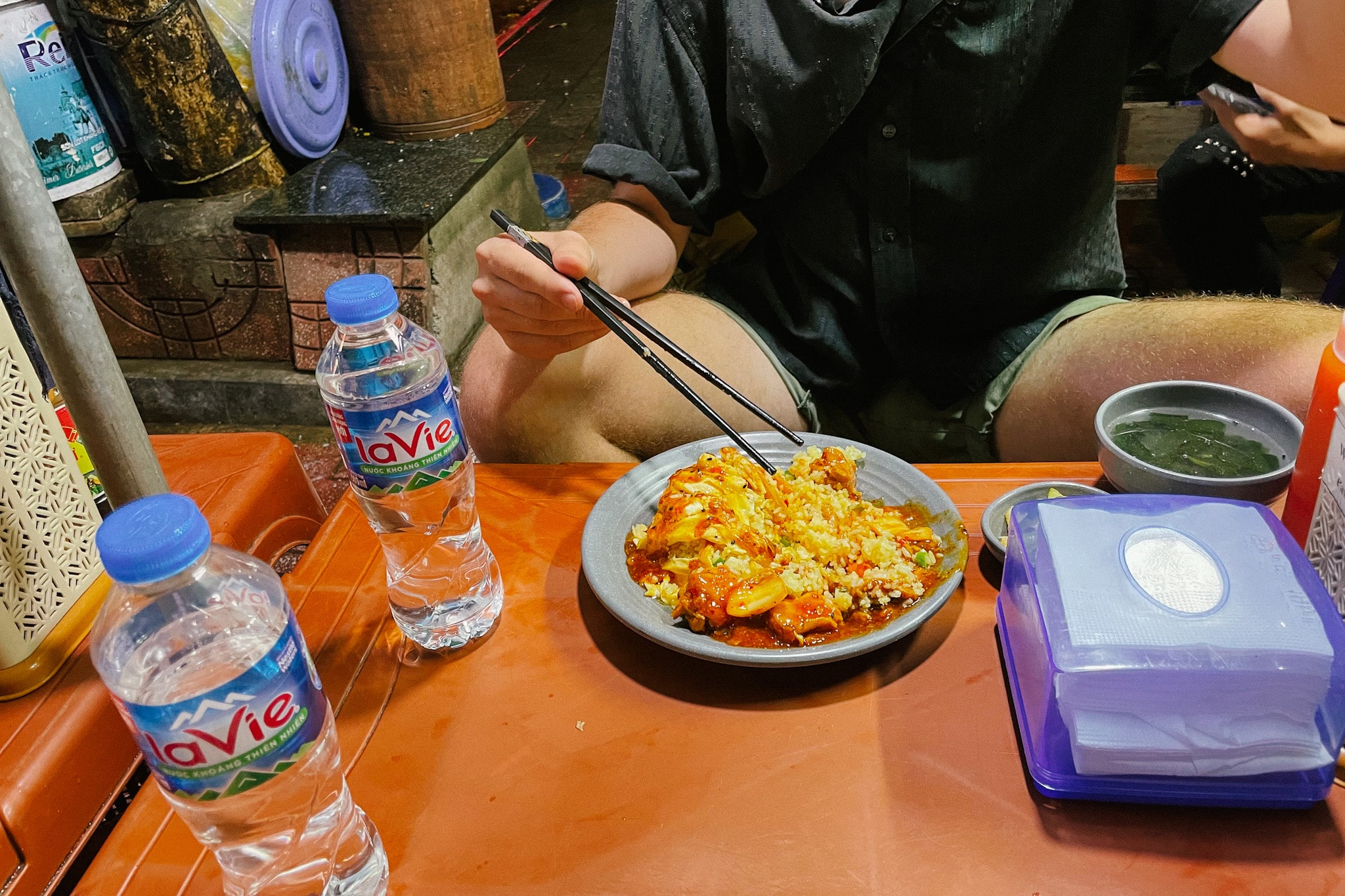 Hanoi street food: Person eating a rice dish called Com Trung with chopsticks at Com Trung Viet Trung