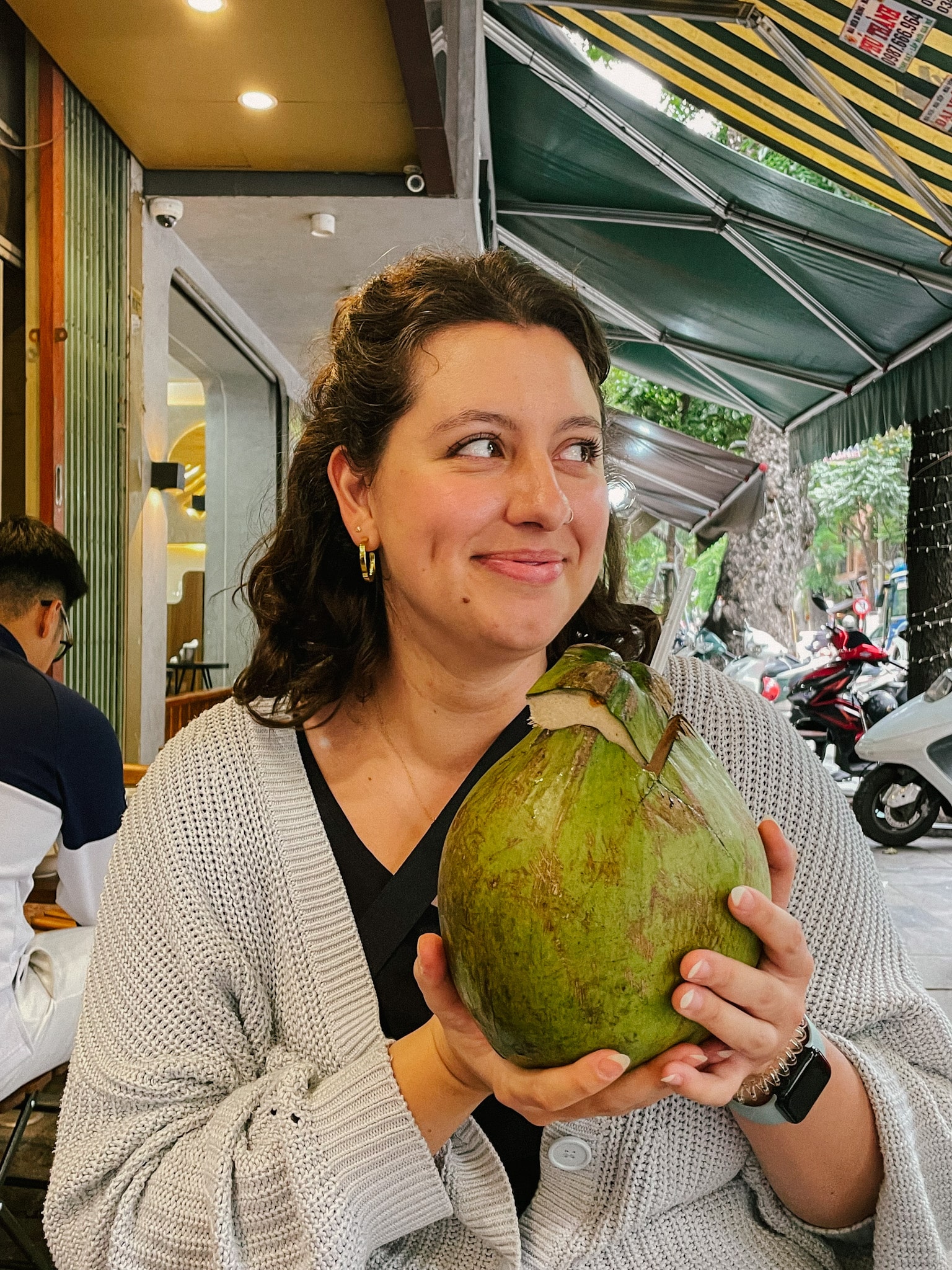 Rachel enjoying a fresh coconut at Xoi Yen in Hanoi, a great spot for where to eat in Hanoi.
