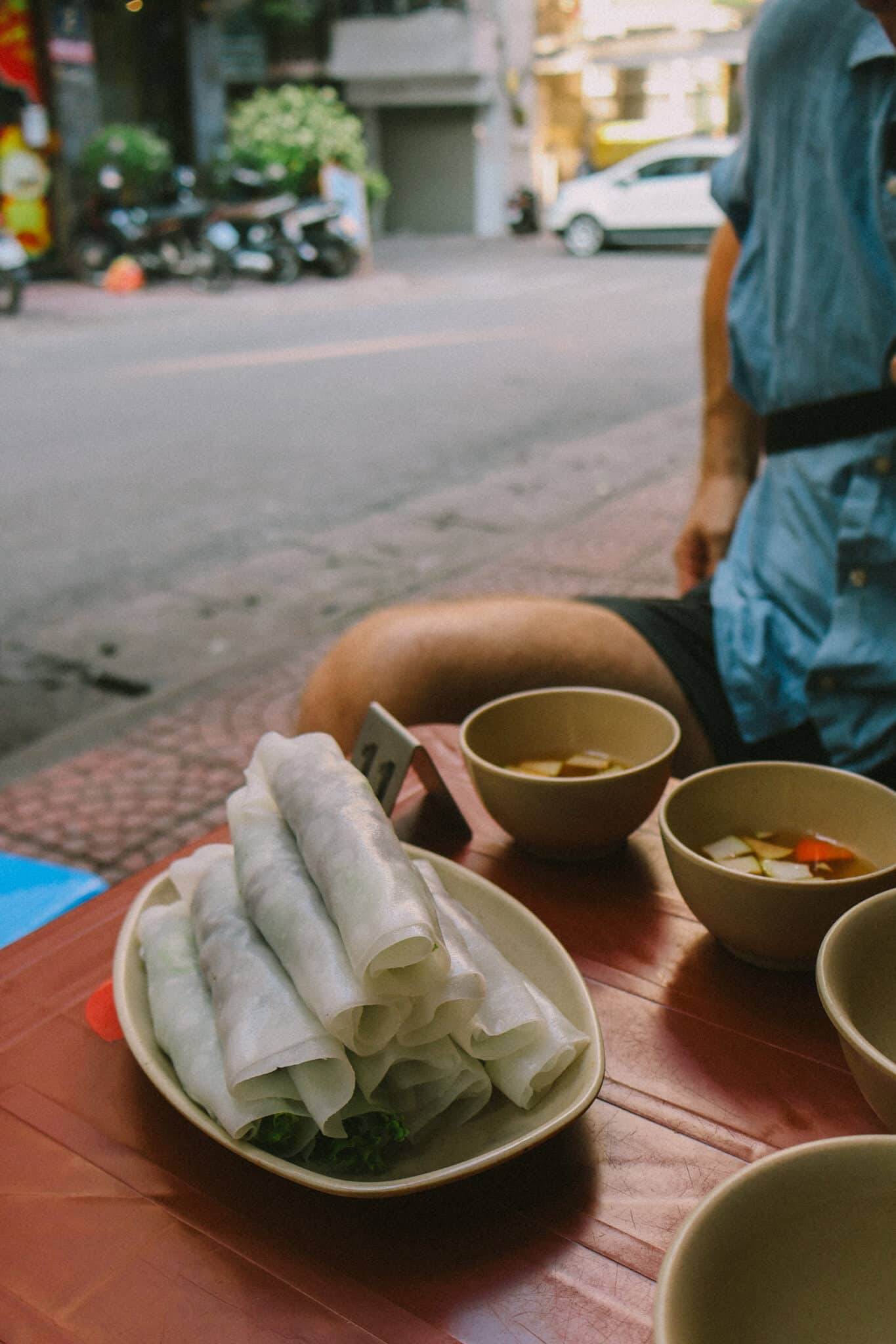 Fresh Vietnamese Pho Cuon spring rolls and dipping sauce at a Hanoi street food stall, Pho Cuon Chinh Thang