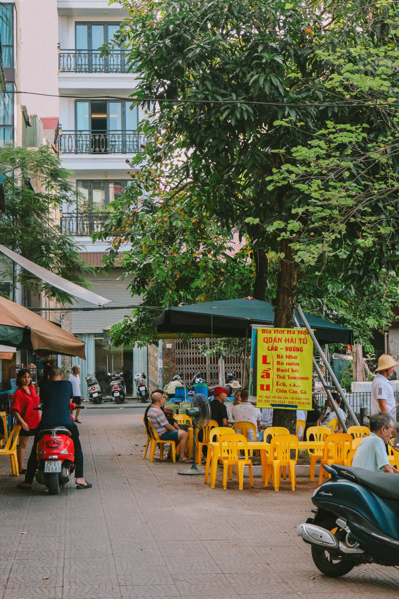 Bia hoi street food stall in Ngoc Ha, Hanoi with yellow tables, serving Vietnamese dishes.