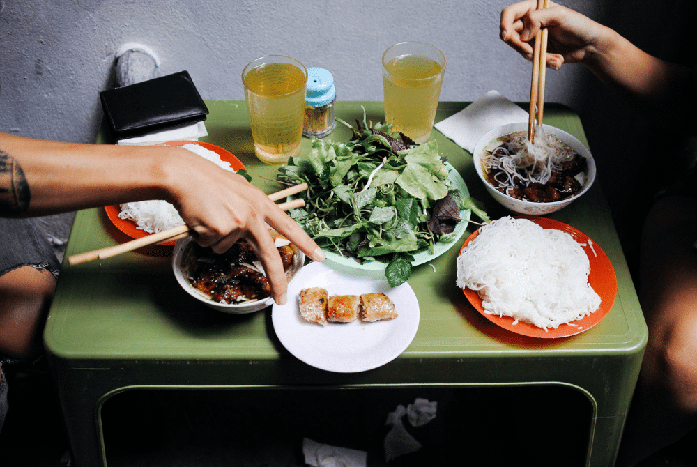 Hanoi street food: People eating bun cha with noodles and fresh herbs at a Hanoi restaurant.